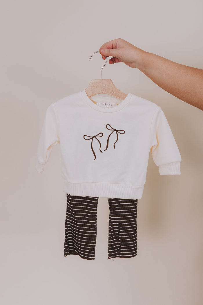 cream sweatshirt with brown bow embroidered design and brown and white striped pants