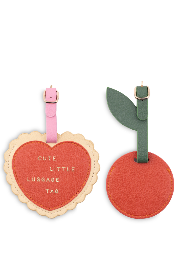 Heart-shaped luggage tag with pink strap and cherry-shaped luggage tag with green strap on a white background