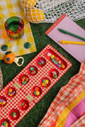 Red gingham mancala board with fruit shaped pieces.