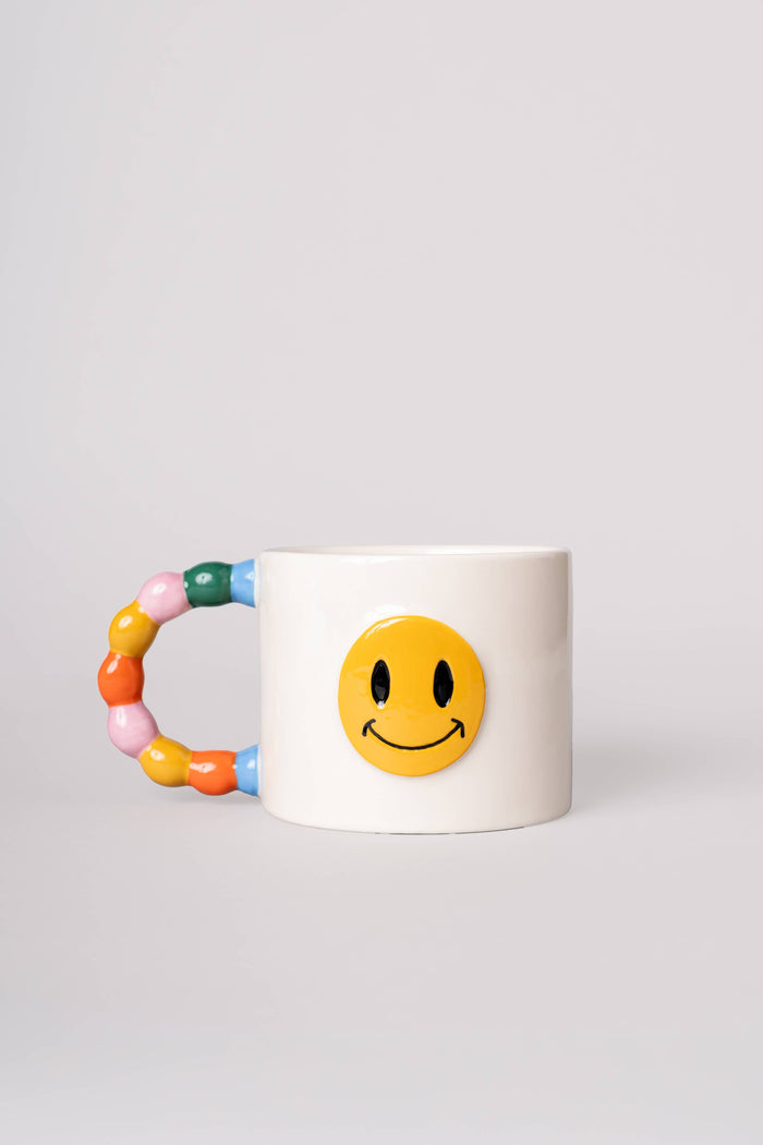 white smiley face mug with colorful handle