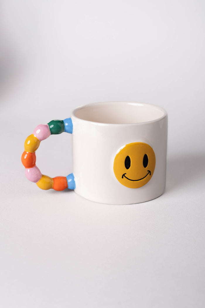 near white off white mug yellow smiley face colorful handle