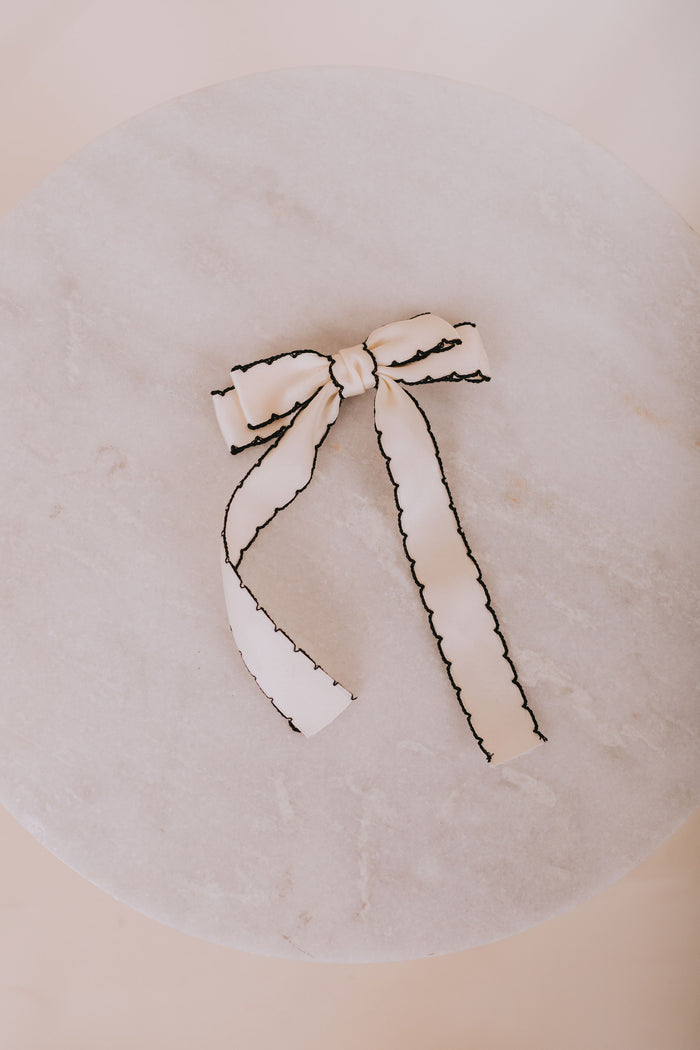 White bow with black trim on a round beige surface