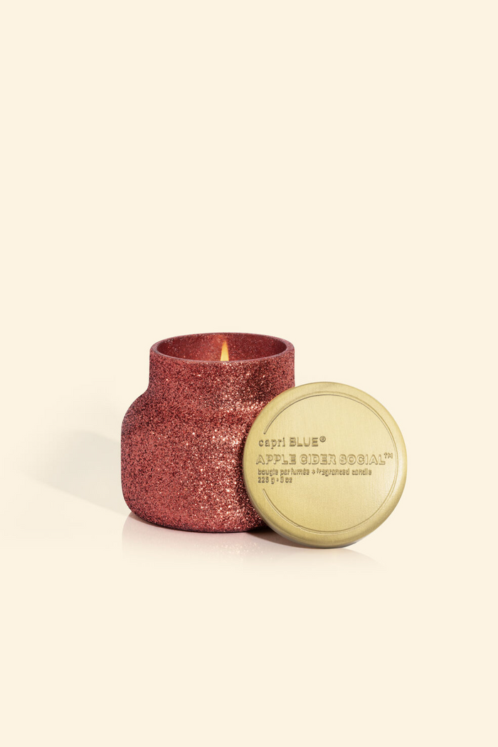 Cranberry colored glittery candle jar with brushed gold lid in scent apple cider social.
