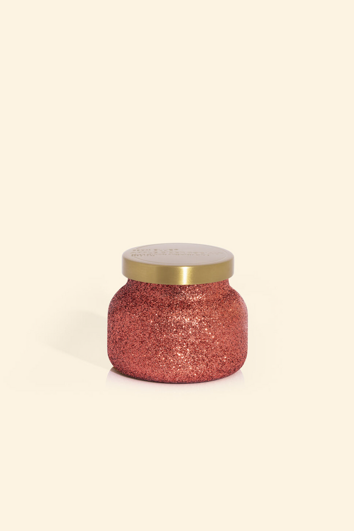 Cranberry colored glittery candle jar with brushed gold lid in scent apple cider social.