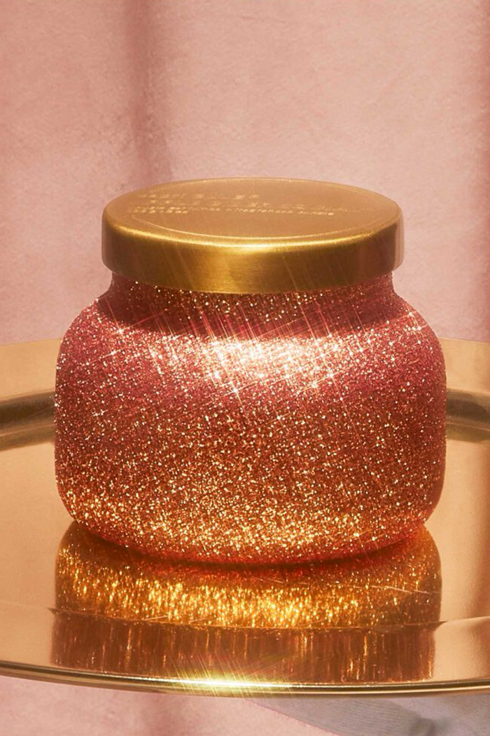 Cranberry colored glittery candle jar with brushed gold lid in scent apple cider social.