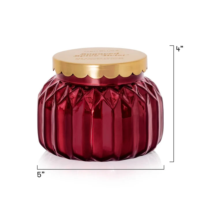 Red faceted jar candle with a gold scalloped lid in scent Sugared Spice Twist by Capri Blue.