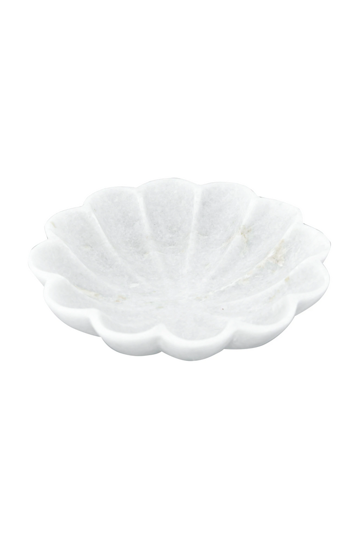 A white marble dish with scalloped edges, resembling a flower shape, placed against a plain background.