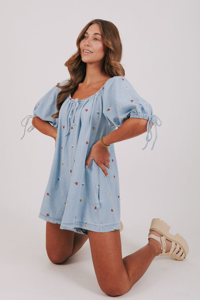 denim romper with embroidered flowers pose