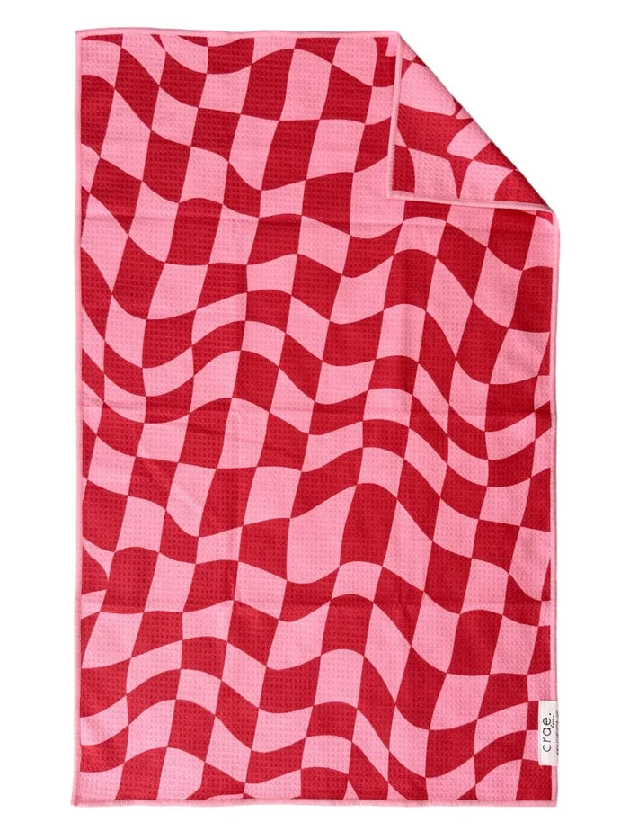 A double-sided microfiber hand towel with a red and pink geometric pattern