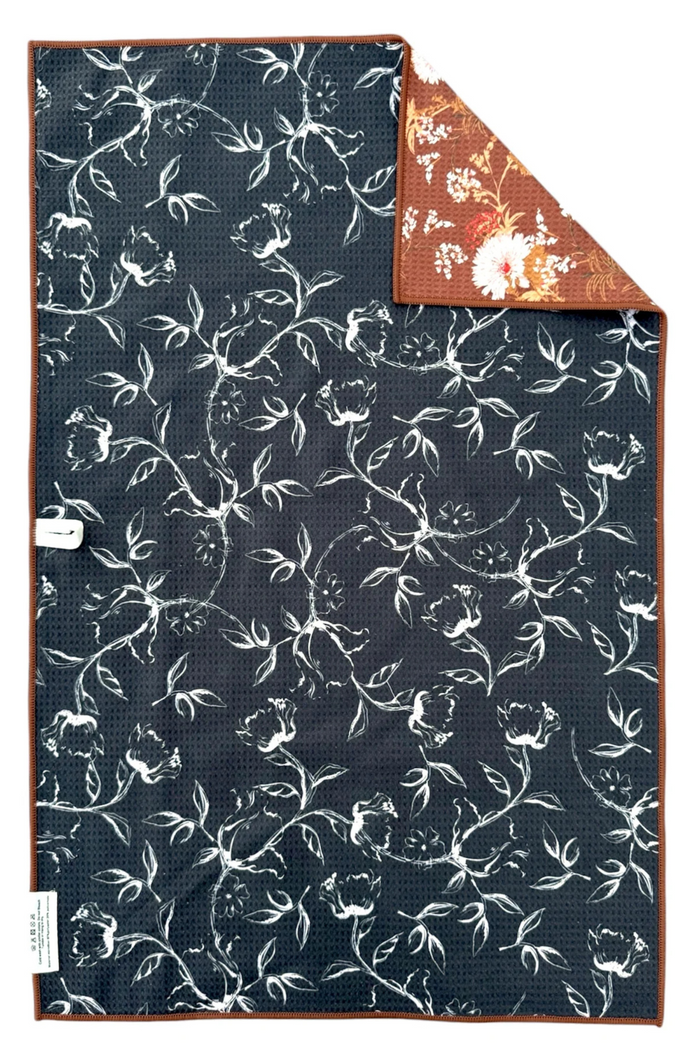 Reversible hand towel with white floral pattern on black background.