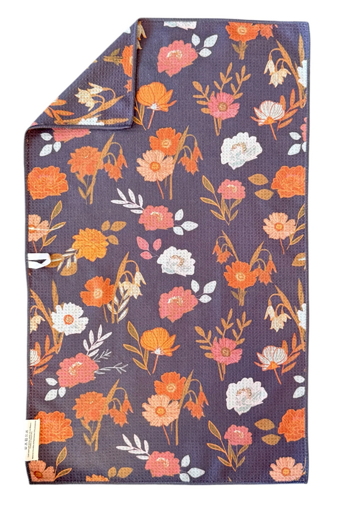 Floral-patterned microfiber hand towel with orange, pink, and white flowers on a dark background