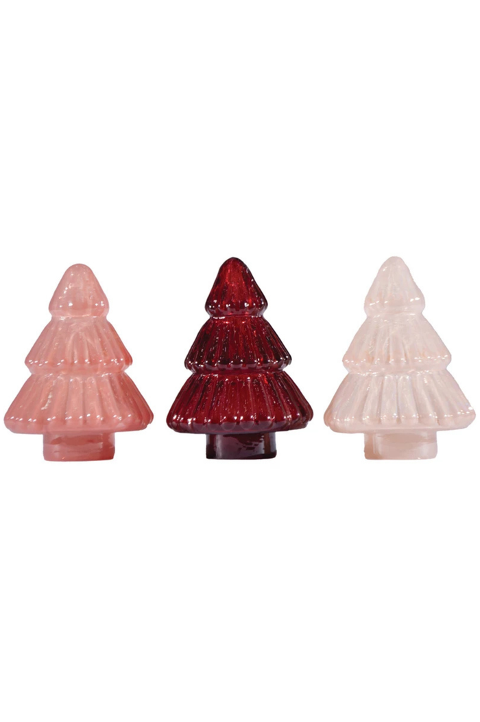 Three glass Christmas tree ornaments in pink, red, and white on a white background