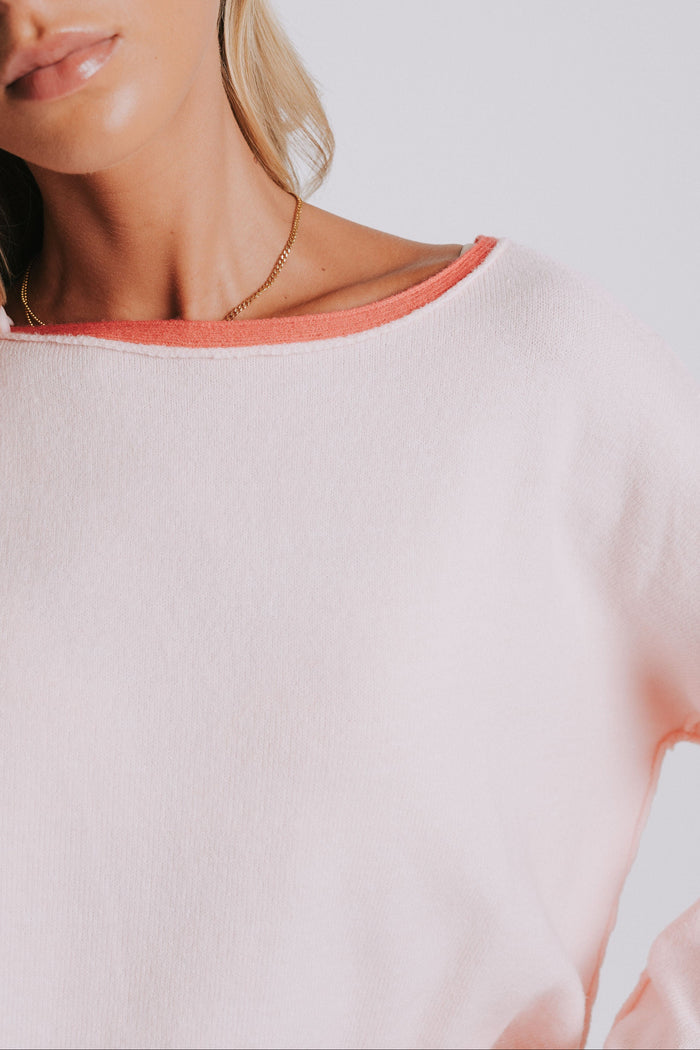 light pink sweater with raw seams and rolled edges neckline