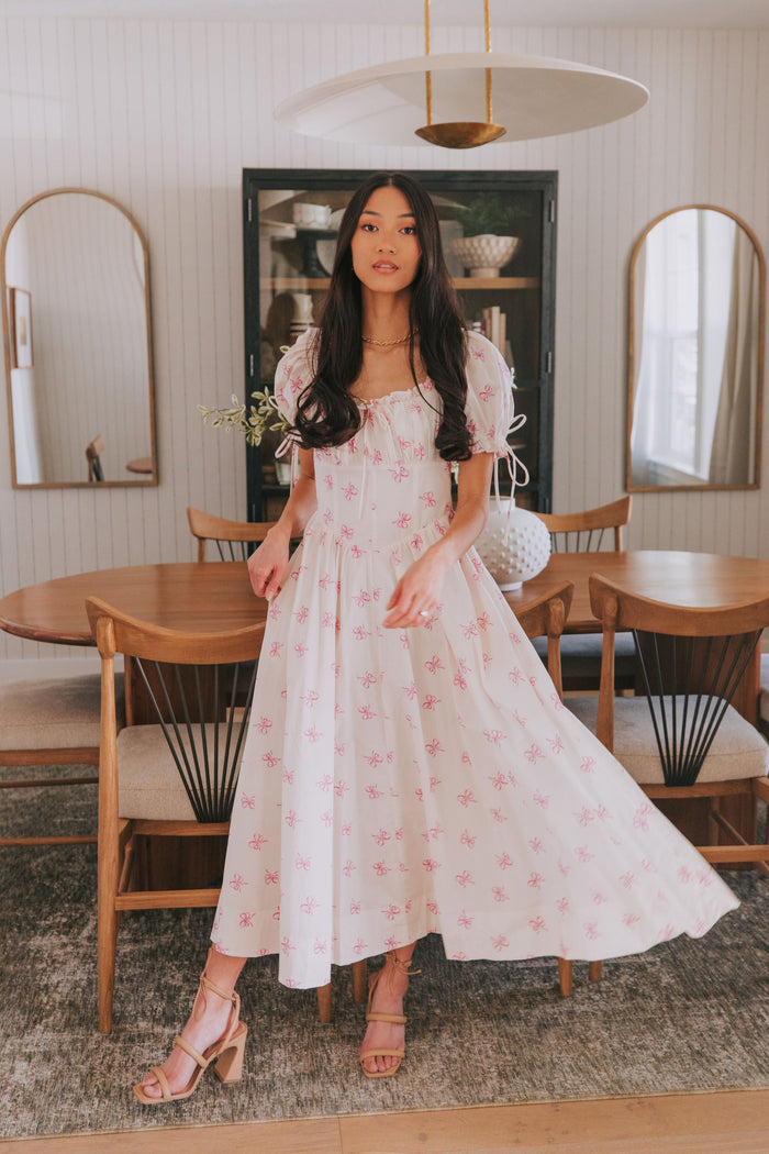 white midi dress with pink bow print and ruched bust and puff sleeves