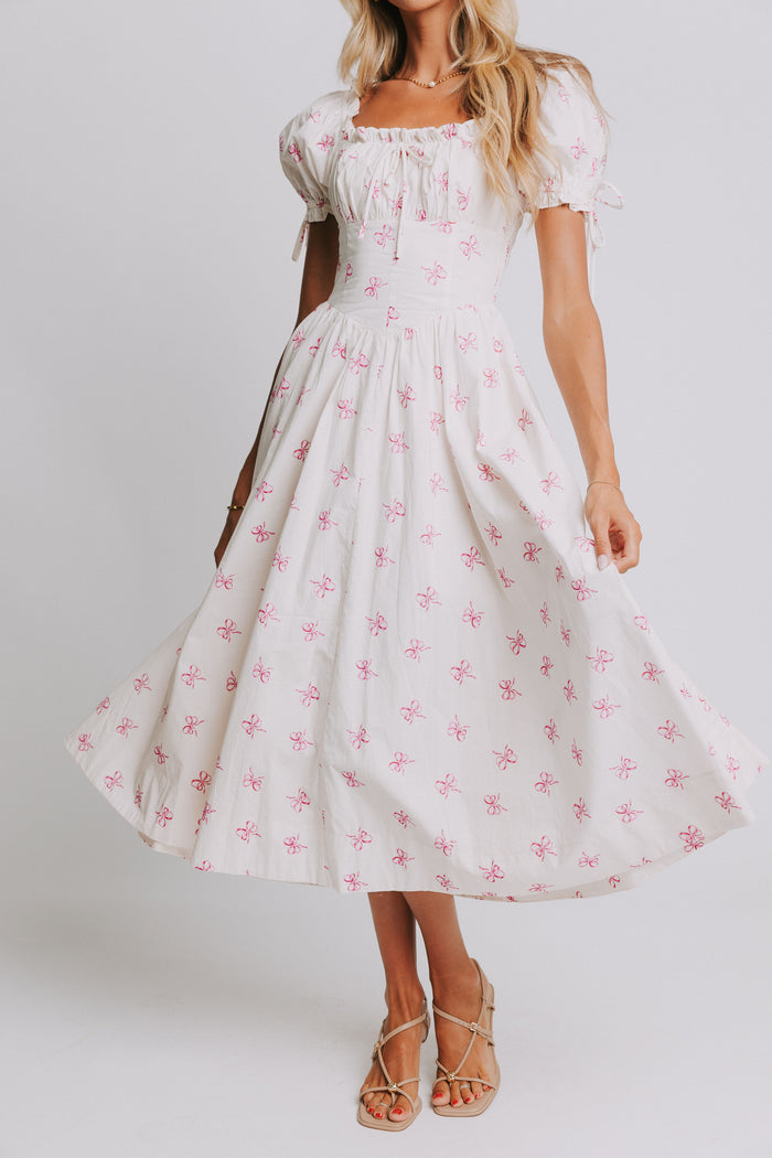 white midi dress with pink bow print and ruched bust and puff sleeves front