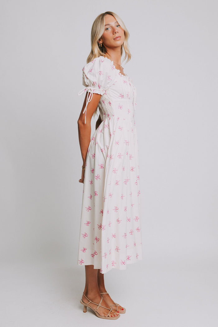 white midi dress with pink bow print and ruched bust and puff sleeves side