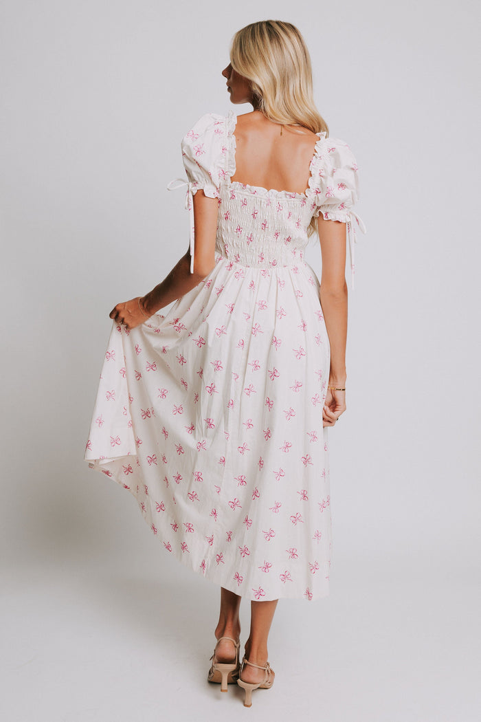 white midi dress with pink bow print and ruched bust and puff sleeves