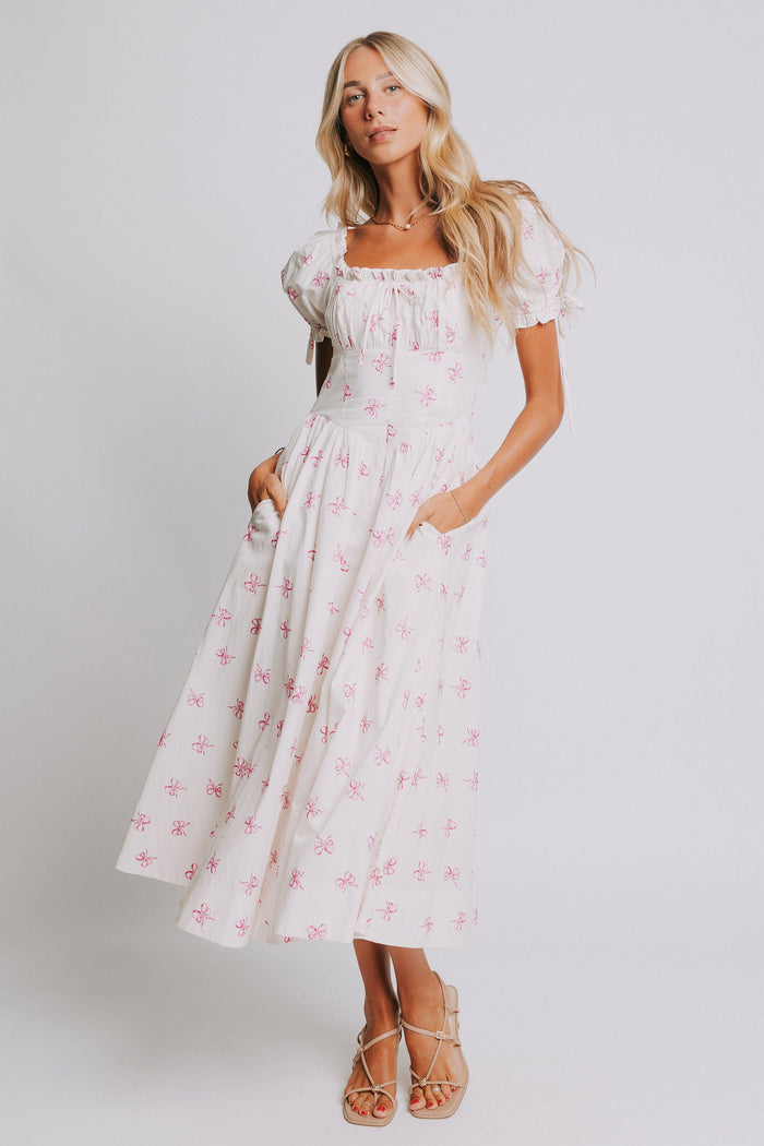 white midi dress with pink bow print and ruched bust and puff sleeves full