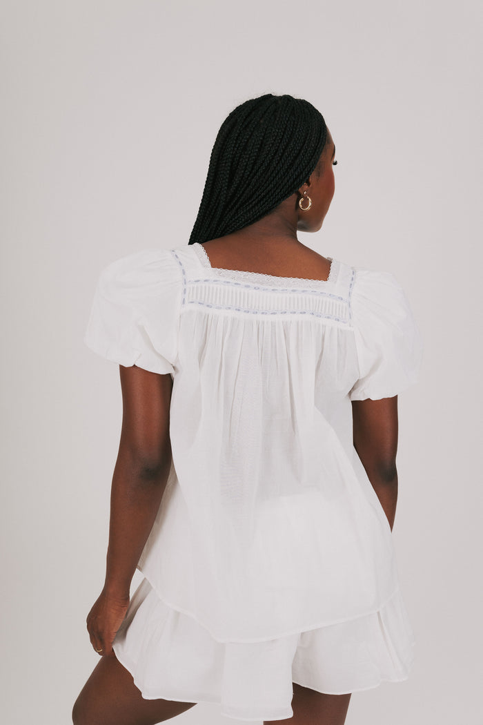 loose white top with blue ribbon detail and lace back