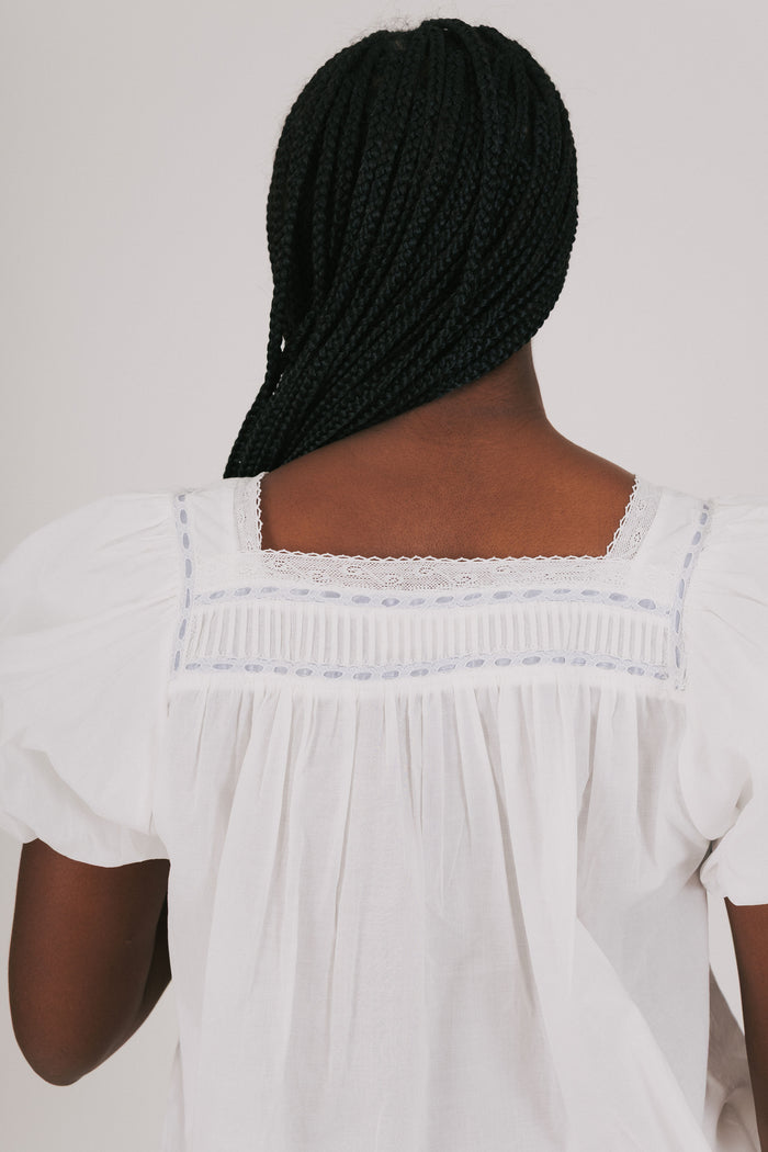 loose white top with blue ribbon detail and lace back close up