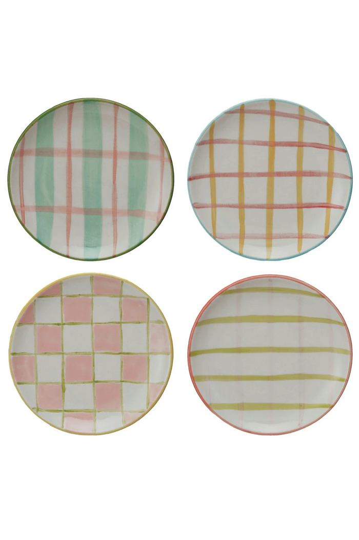 A set of four hand-painted stoneware plates with various patterns, including checkered and striped designs, in multicolored hues.