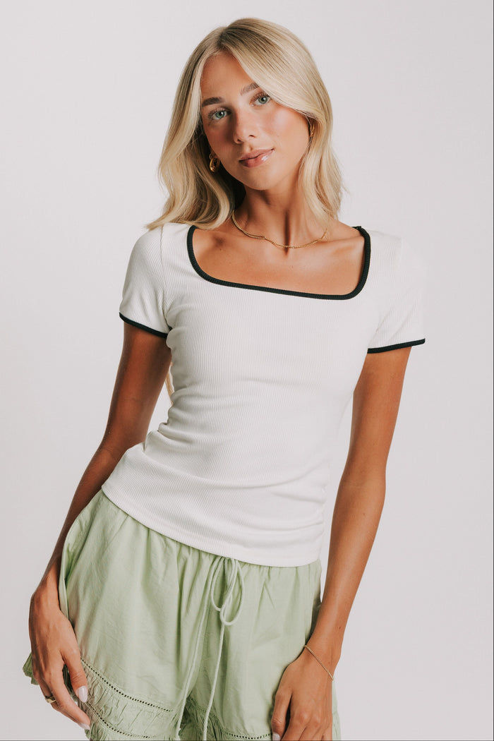 white ribbed top with black trim on neckline and sleeves