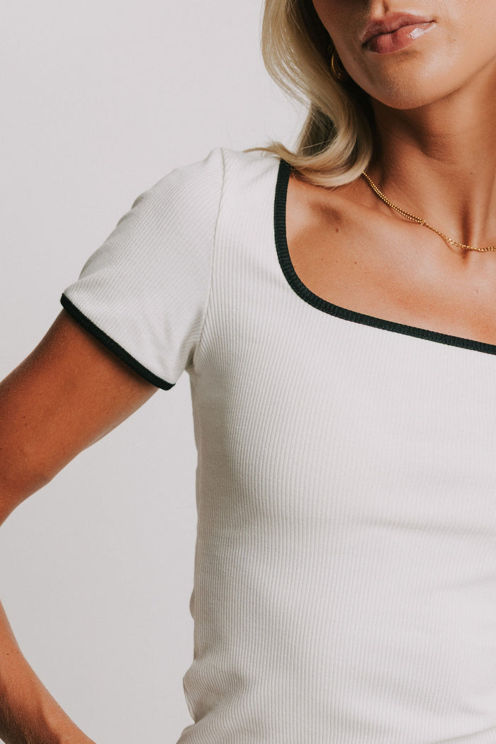 white ribbed top with black trim on neckline and sleeves close