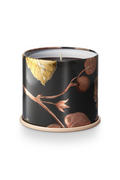 Candle in a black container with floral design on a white background