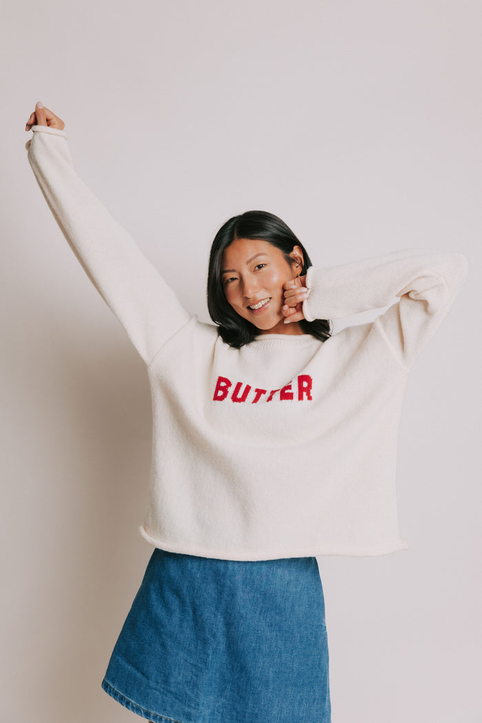 cream sweater with rolled edges and butter emblem