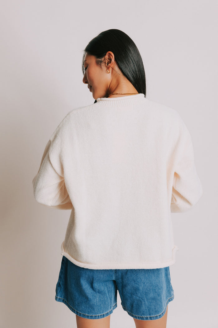 cream sweater with rolled edges and butter emblem back