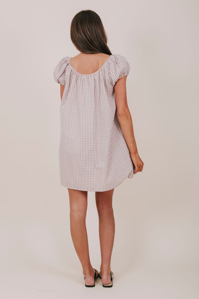 white and tan gingham dress with round neckline, bubble sleeves, and a bow detail. Mini-knee length tent dress gathered details