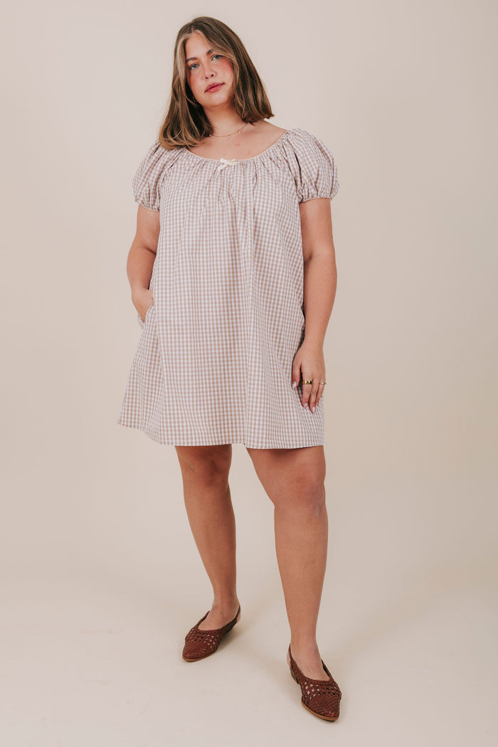 white and tan gingham dress with round neckline, bubble sleeves, and a bow detail. Mini-knee length