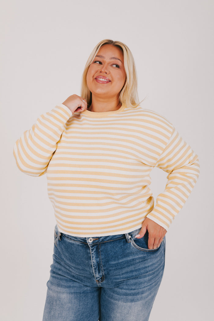Woman wearing a striped sweater and blue jeans against a plain background
