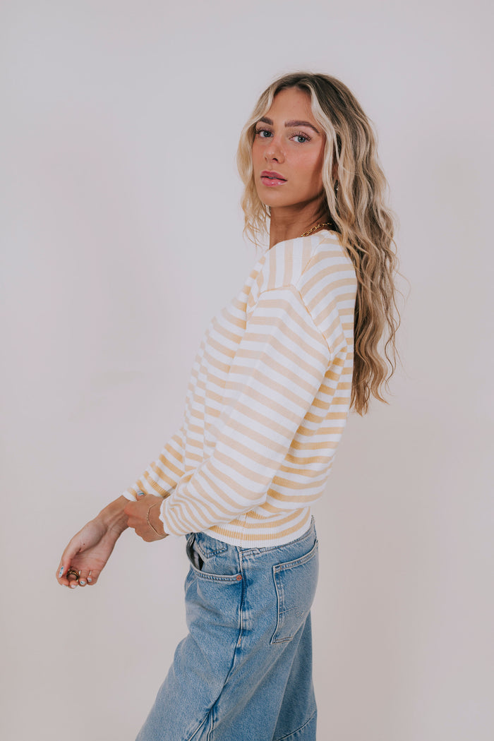 Woman wearing a striped sweater and jeans against a plain background