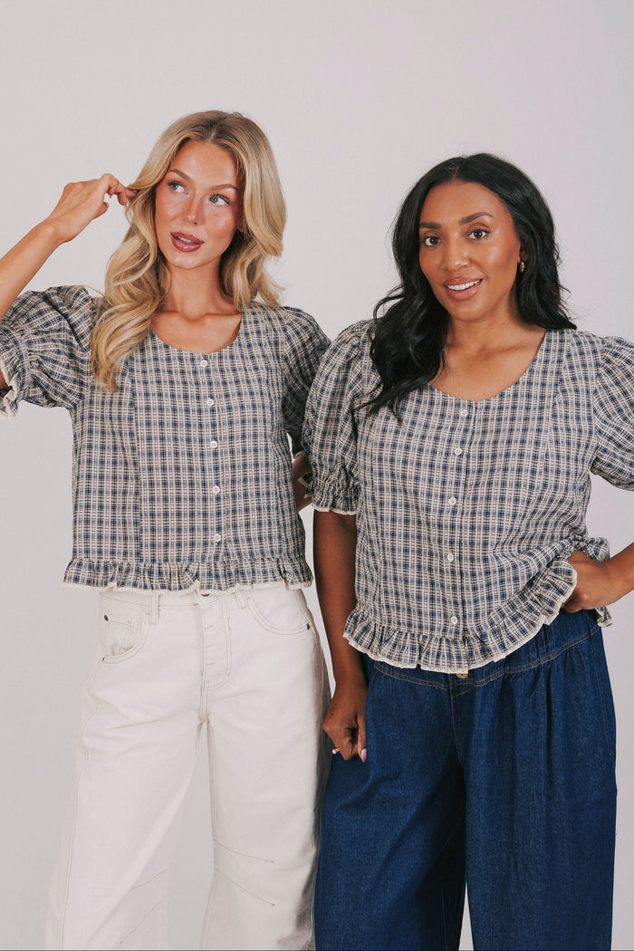 Plus size plaid navy blouse with button up front and short puff sleeves. Round neckline and ruffle hem.