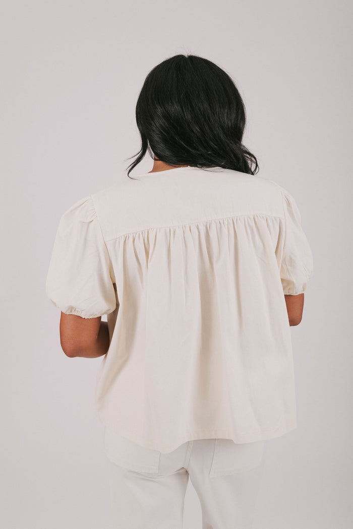 ivory colored blouse with short puff sleeves and gathered detail