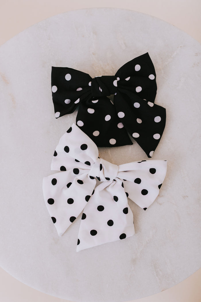 Black and white polka dot hair bows on a neutral background