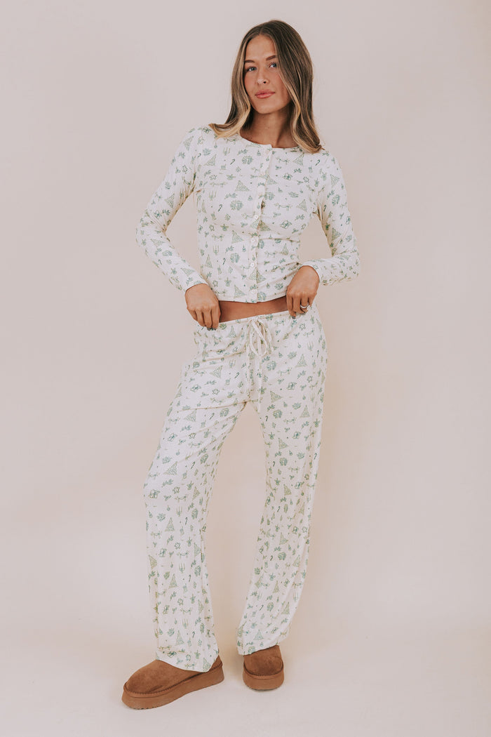 Woman wearing a christmas patterned pajama set against a plain background