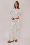 Woman wearing a christmas patterned pajama set against a plain background
