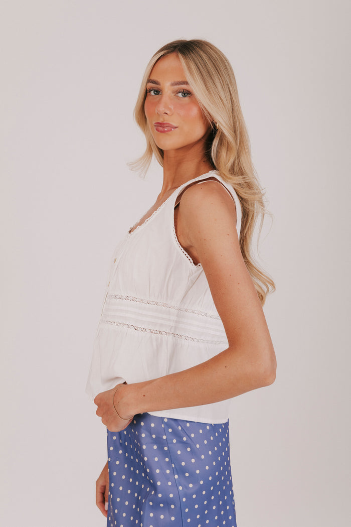 White sleeveless blouse with gathered lace, and pin-tucked details.