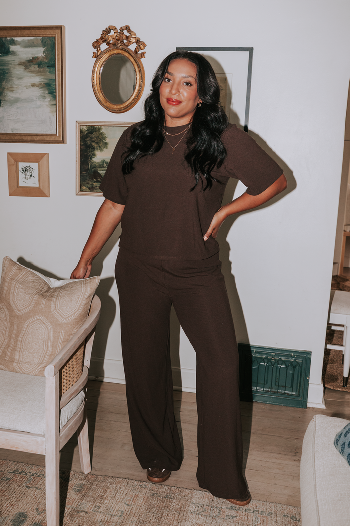 Woman in a brown outfit standing in a living room with decorative elements.