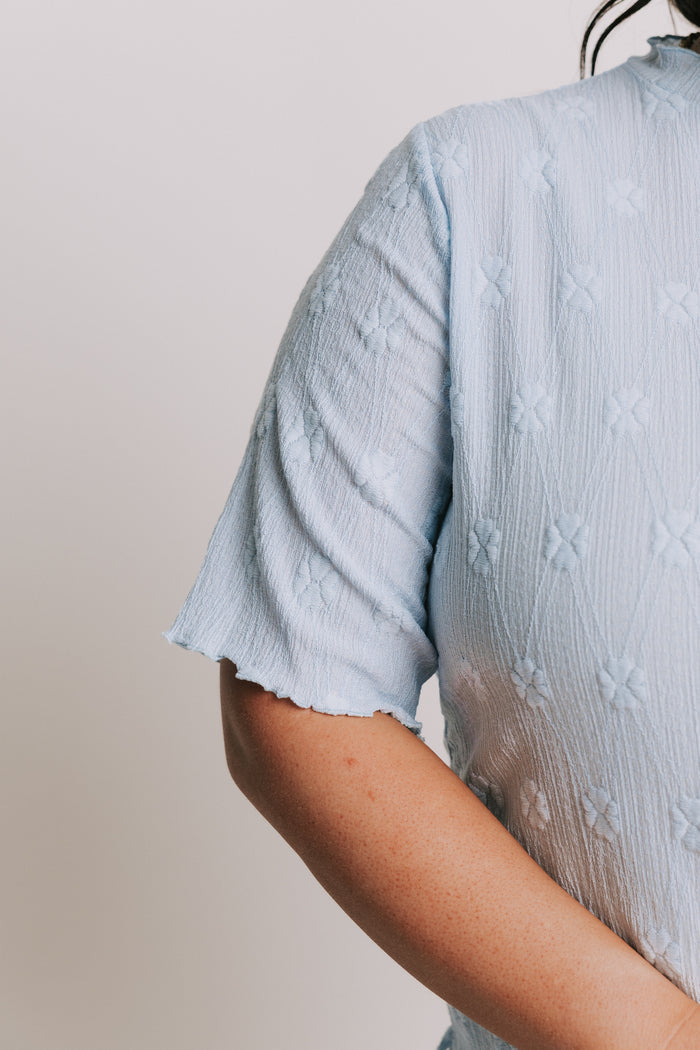 light blue top with textured pattern and mock neck sleeves