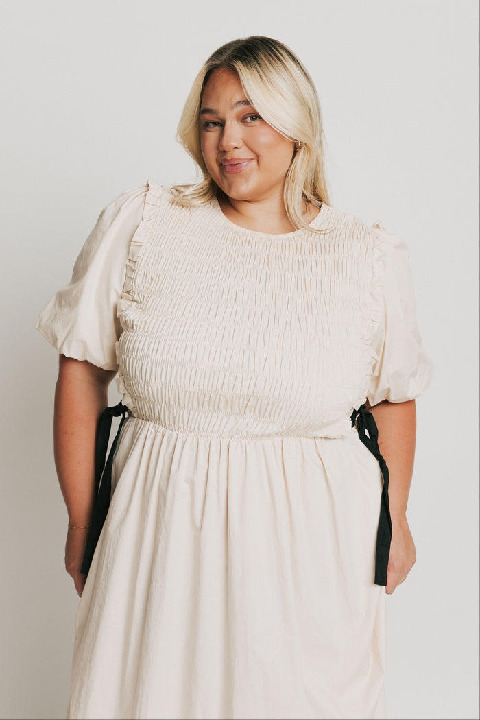 cream midi dress with black bow accents bodice