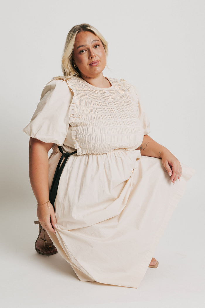 cream midi dress with black bow accents pose