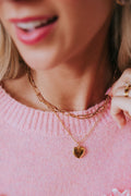 Double layered gold colored necklace with a paper clip chain and a heart pendant.