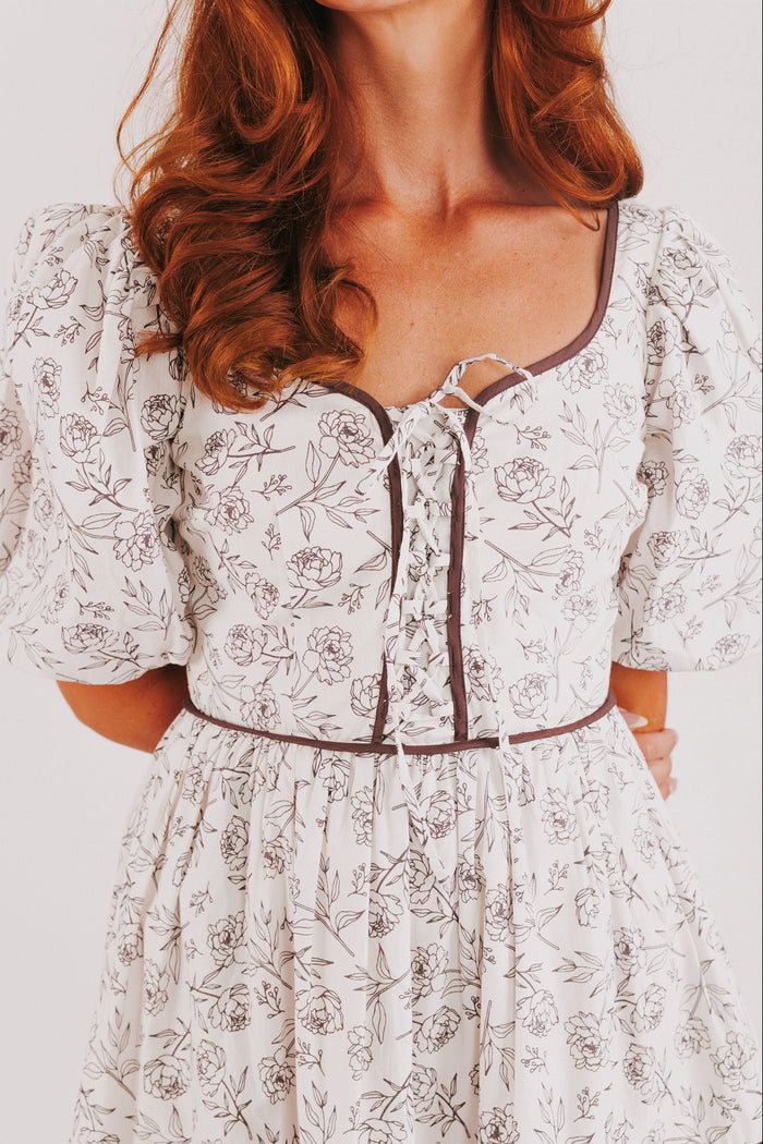 white tiered dress with brown floral pattern and puff sleeves bodice