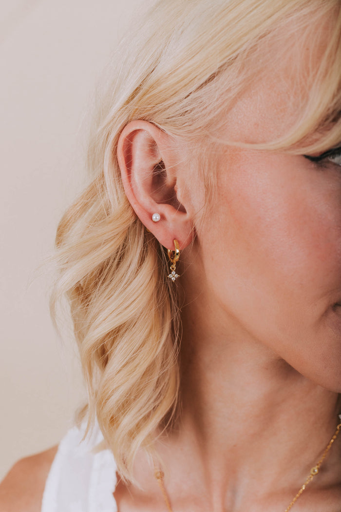 Model wearing gold plated hoop earring with rhinestone flower clover dangle