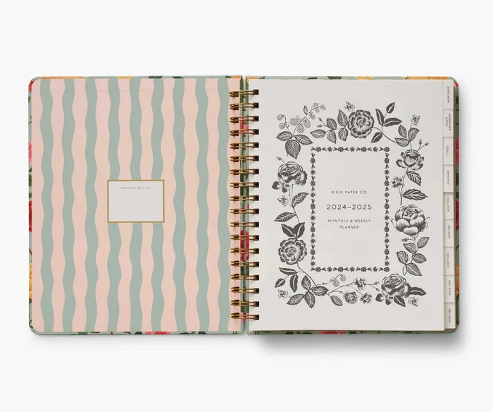 Open planner with floral design and striped cover on a white background