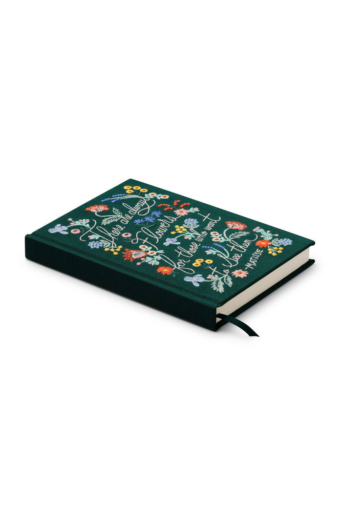 Green journal with embroidered floral designs on a white background