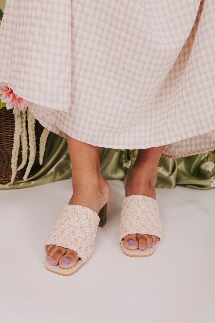 Close-up of feet wearing floral-patterned open-toe shoes with a light background